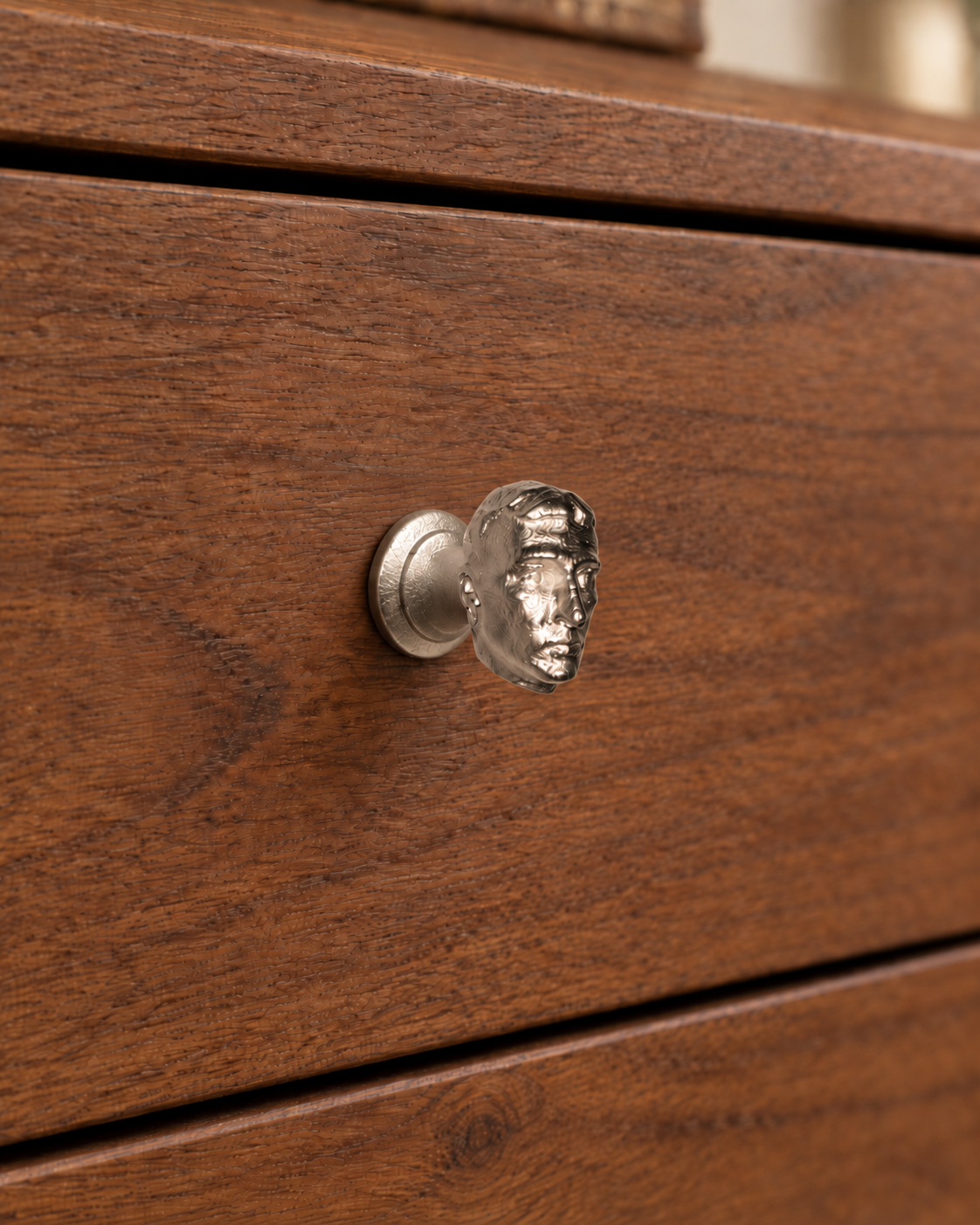 Human-head cabinet knob mounted on a wooden drawer