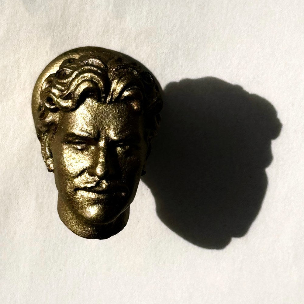 A metal knob of Owen’s head casting a shadow on white paper